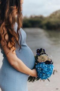 Pregnant woman holding a blue flower bouquet. vitamin