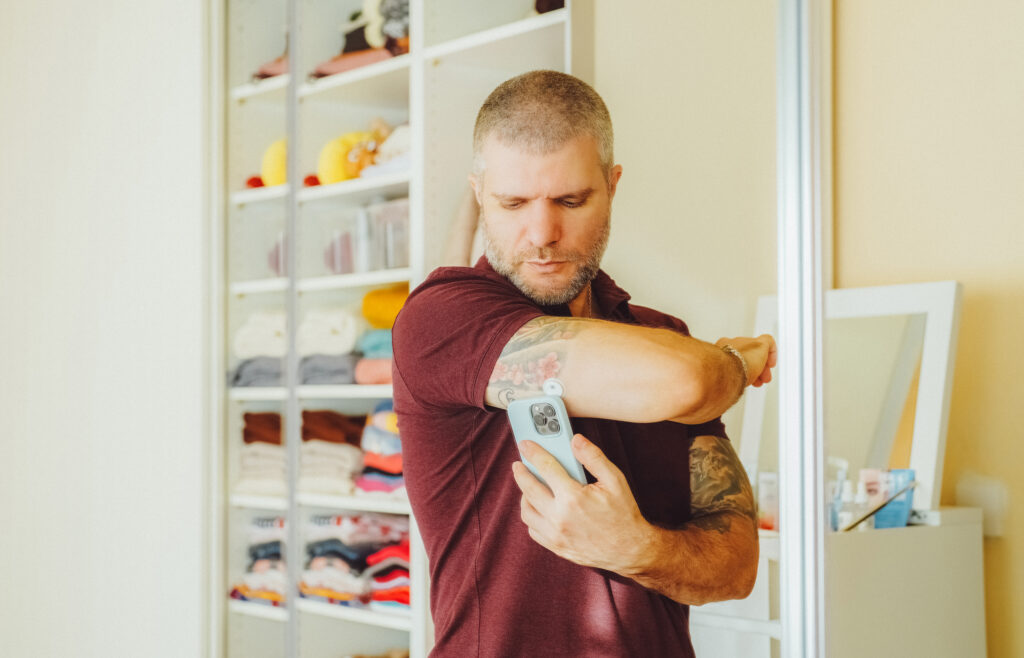 Man is wearing small sensor on the back of upper arm for measuring glucose levels due to diabetes.
