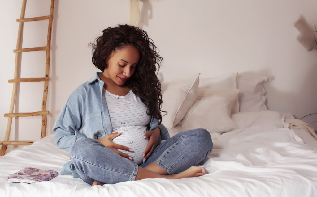 young pretty african american woman pregnant laying in bed, lifestyle people concept close up